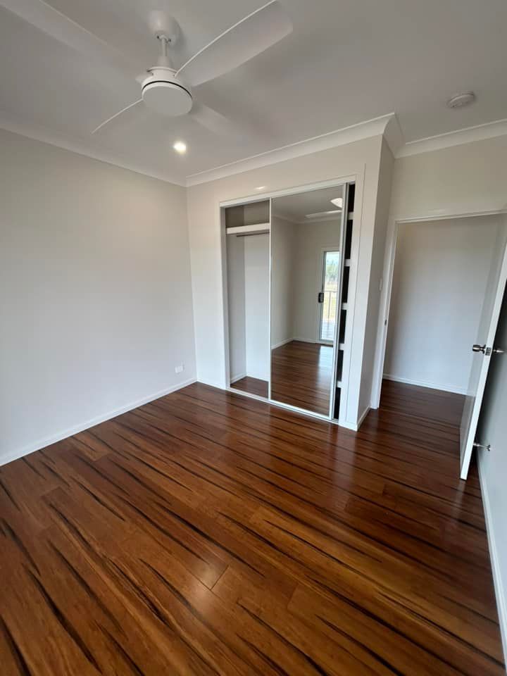 Classic Queensland Homes Presents a Charming Bedroom Featuring Elegant Hardwood Floors — Builder In Gympie, QLD