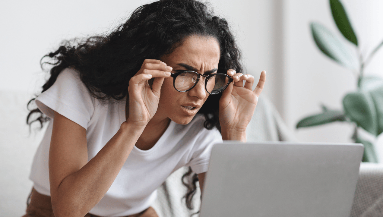 Reader squinting at a laptop, illustrating how vague or overcomplicated writing makes content harder to understand.