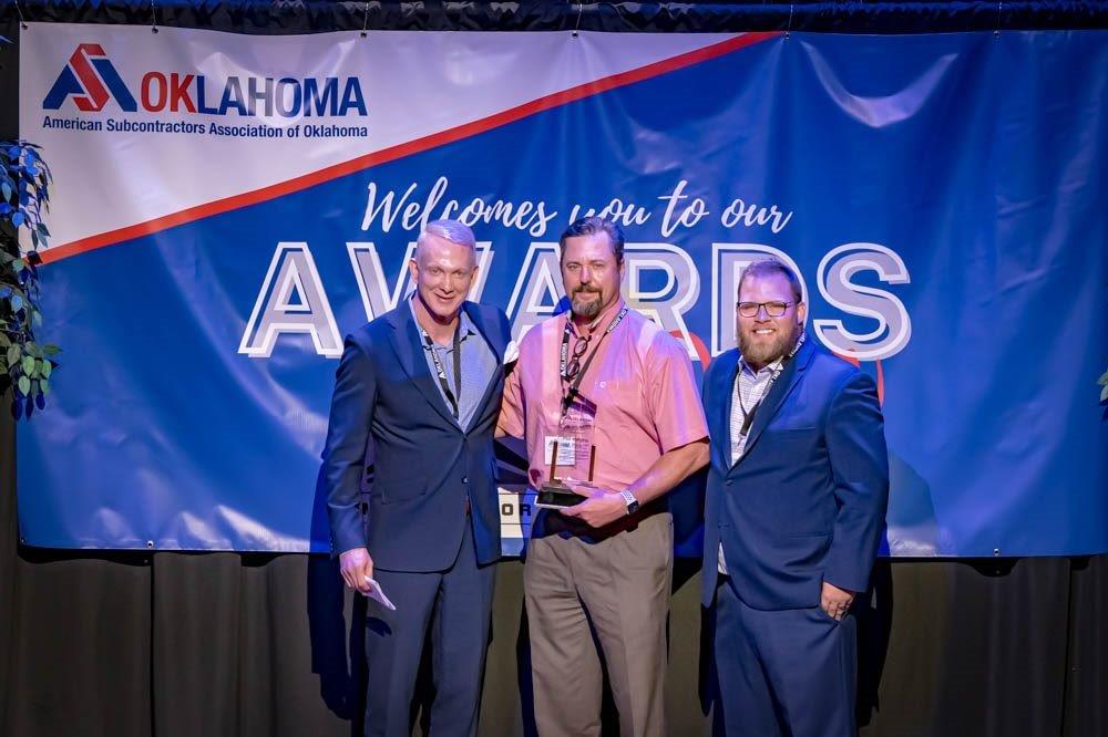 Three men are standing in front of a sign that says oklahoma awards.