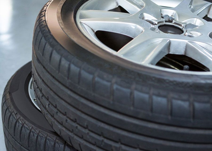 Stacked car tires with a silver alloy wheel on top, close-up view