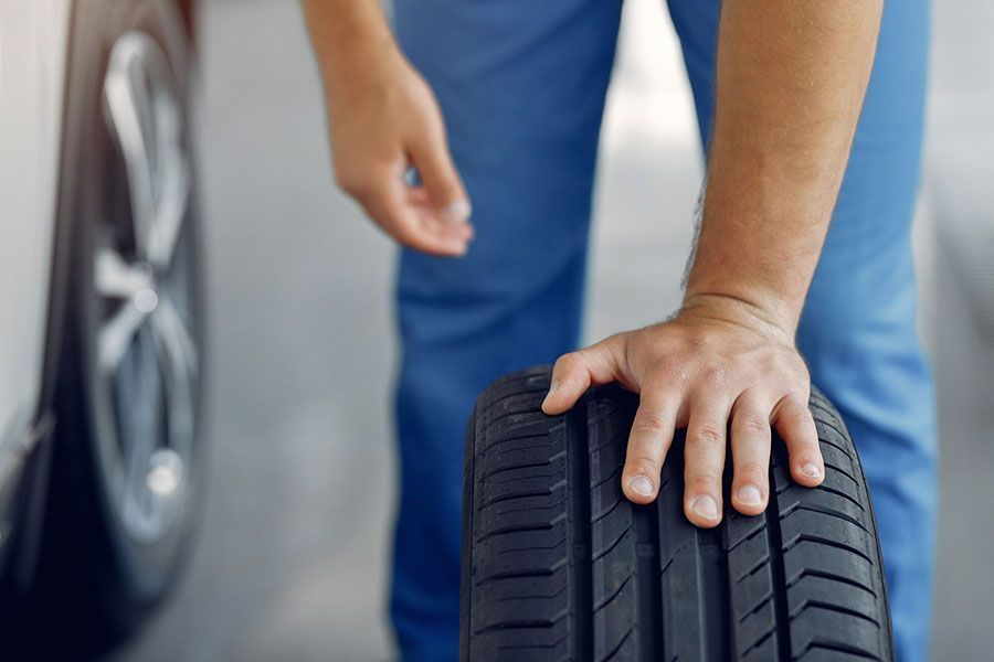 Person checking a car tire with a hand in a garage.