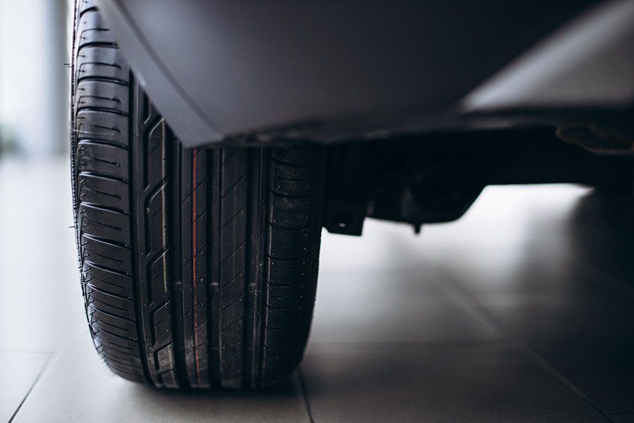 Close-up of a car tire and wheel on a smooth floor, viewed from the side