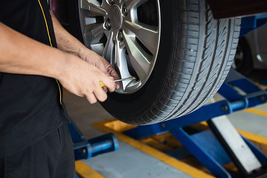 Mechanic tightening a car wheel lug nut on a lift in a garage