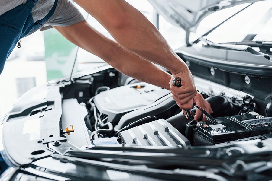 Mechanic inspecting a car engine bay with a wrench in a garage