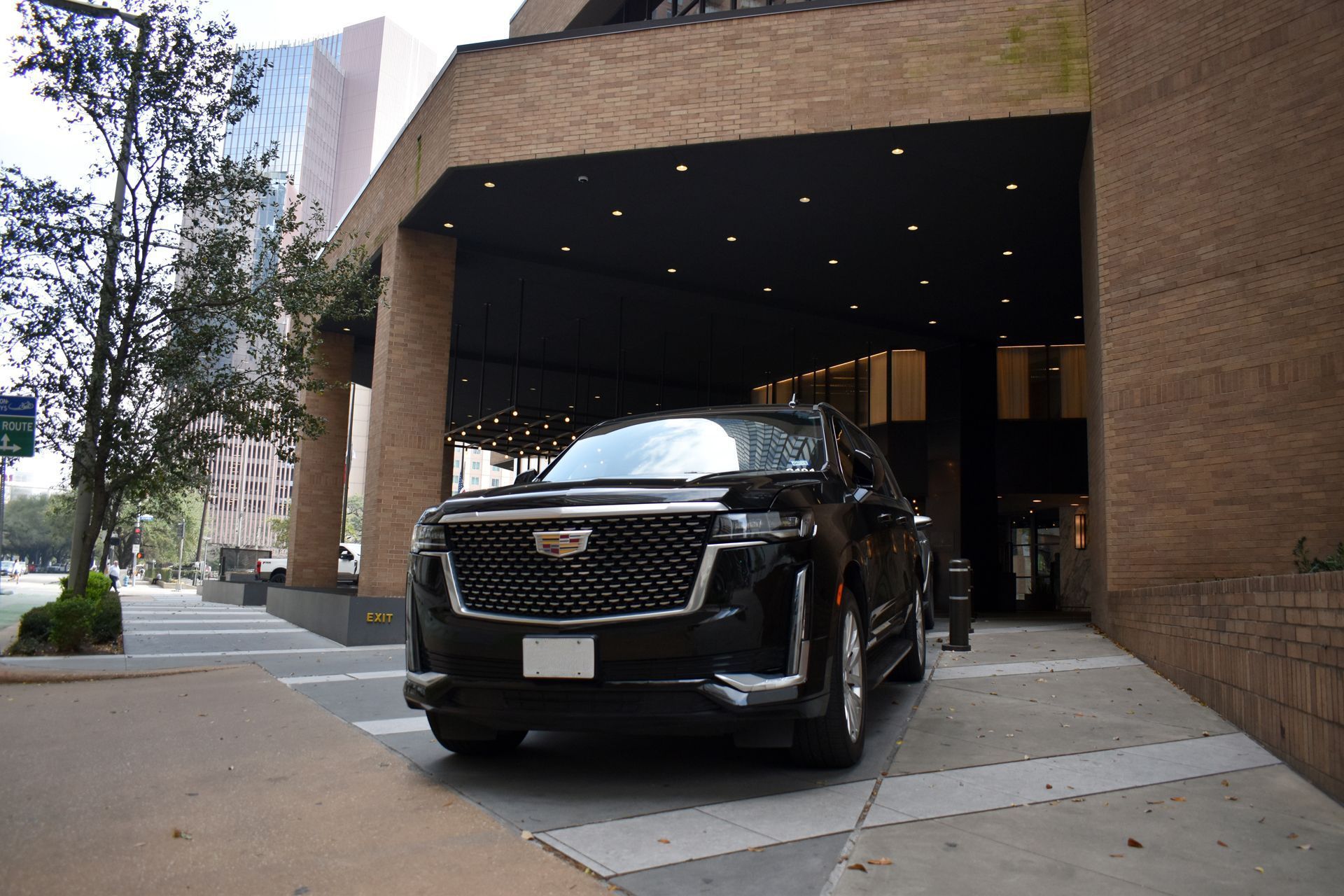 Black Cadillac SUV at a hotel entrance under a covered driveway