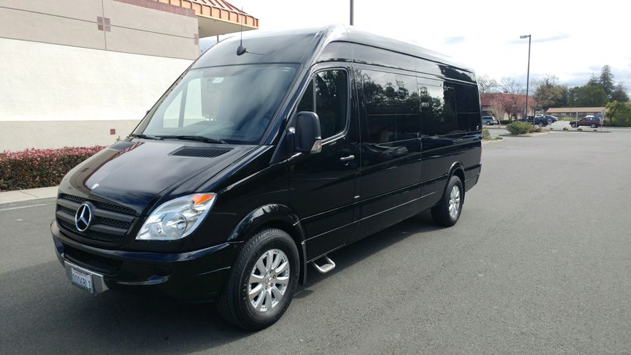 Black Mercedes Sprinter van parked in a lot beside a building under an overcast sky