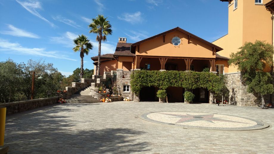 Stone courtyard before a rustic building with palm trees and a circular pattern in the pavement