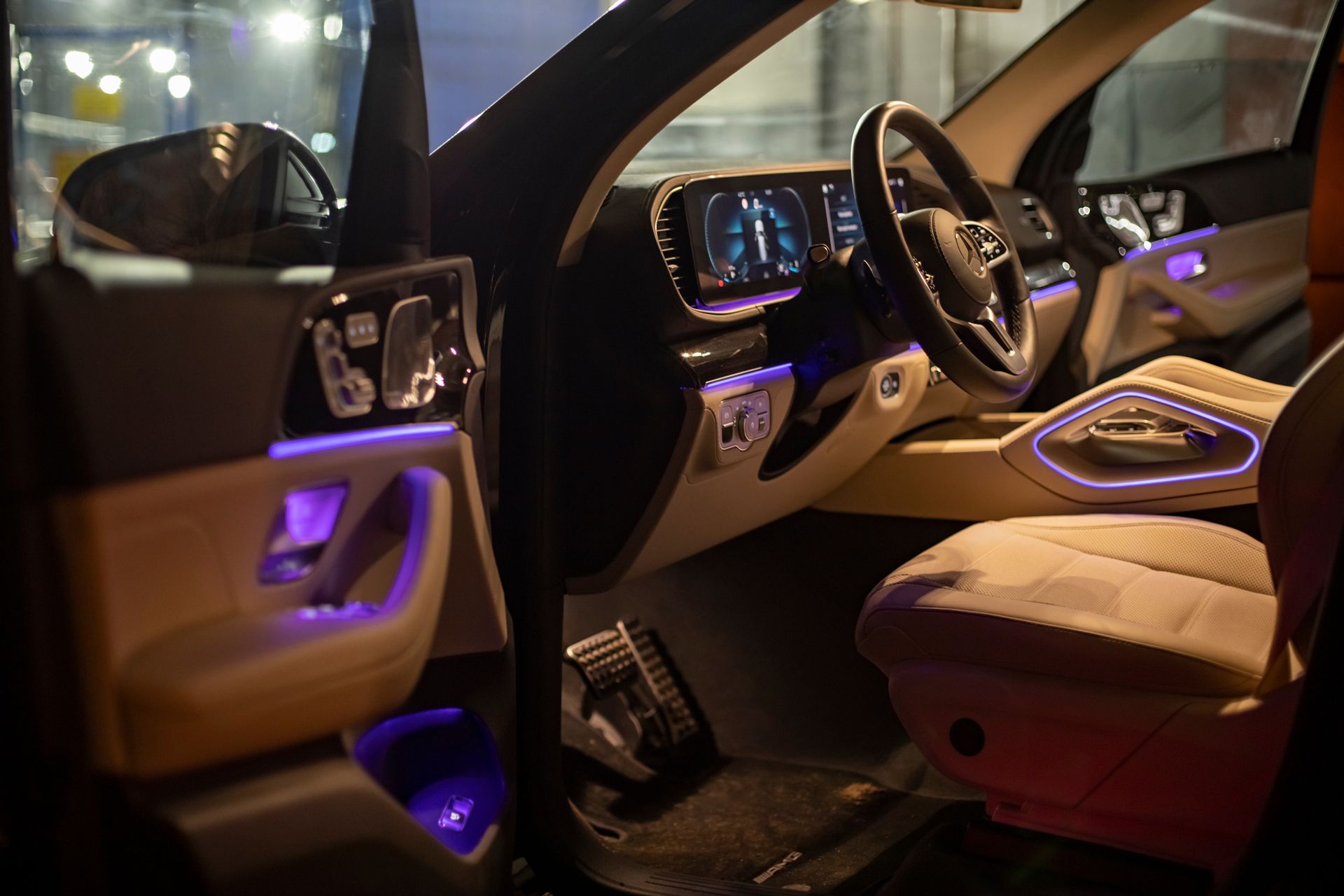 Luxury car interior with purple ambient lighting and open driver’s door