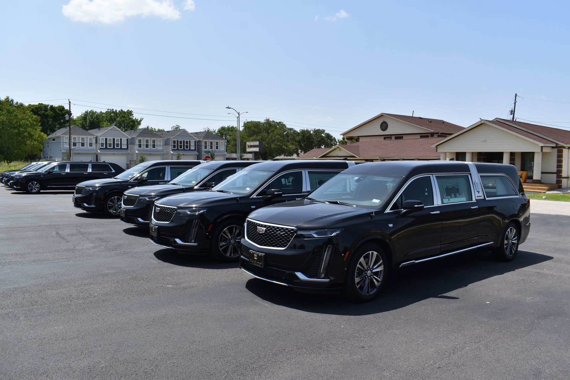 Row of black SUVs parked in a lot under a clear sky