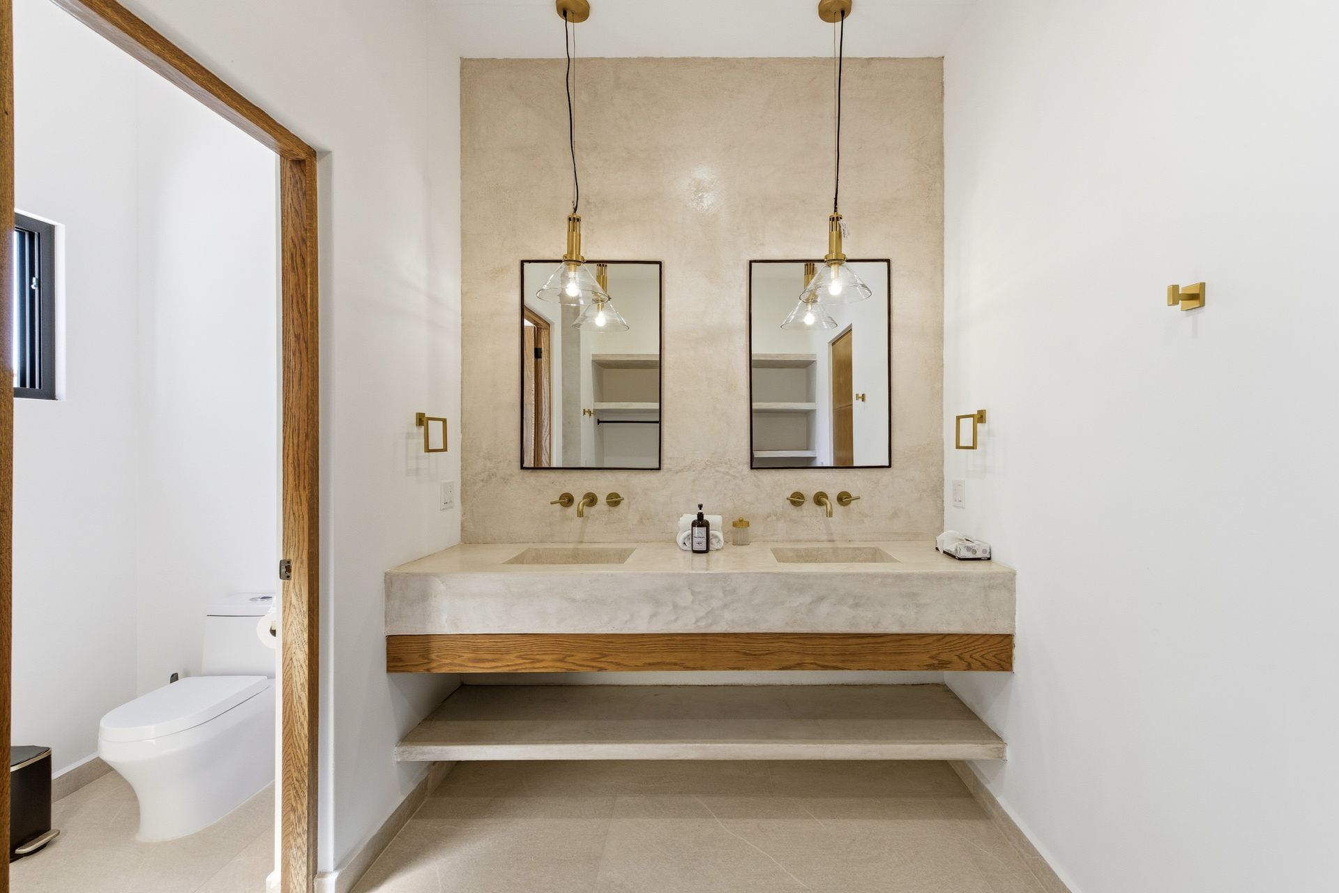 A modern bathroom featuring a floating stone double vanity with wood trim, two rectangular mirrors, and hanging lights.