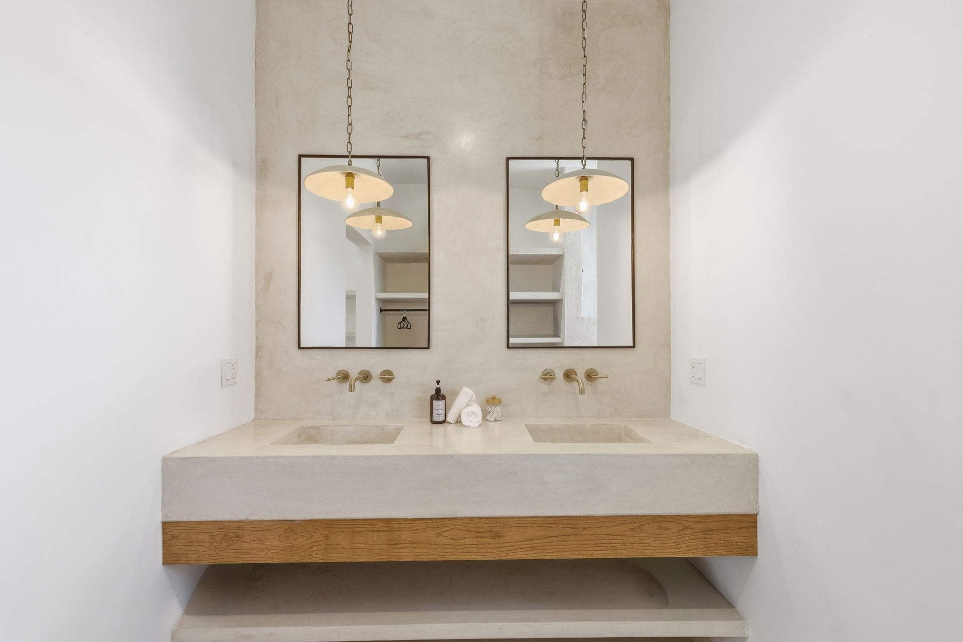 A double vanity with two rectangular mirrors, pendant lights, and a stone-topped counter with wood accents in a bathroom.