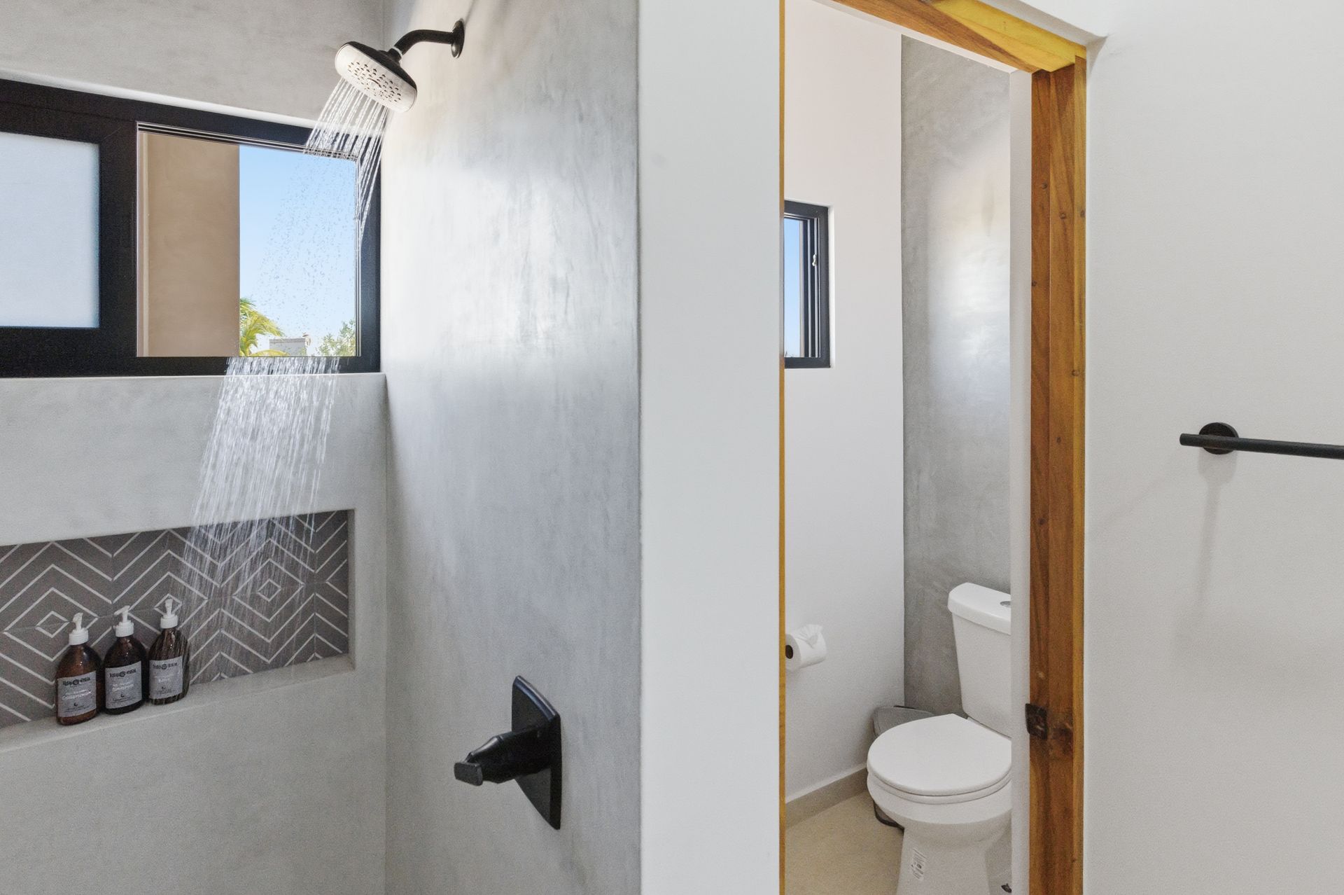 A modern bathroom with a walk-in shower featuring geometric tile niches and a separate toilet room.
