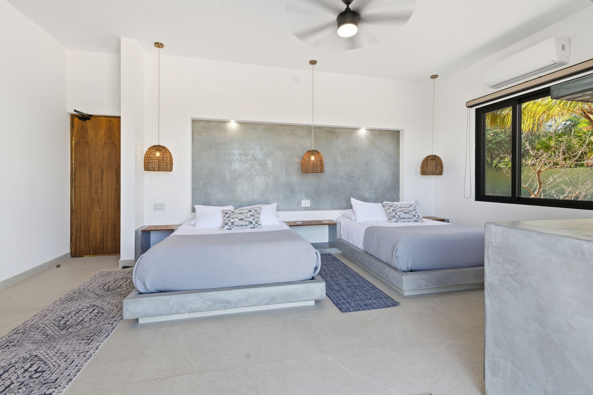 Bedroom with two beds, concrete accents, pendant lights, and large window.
