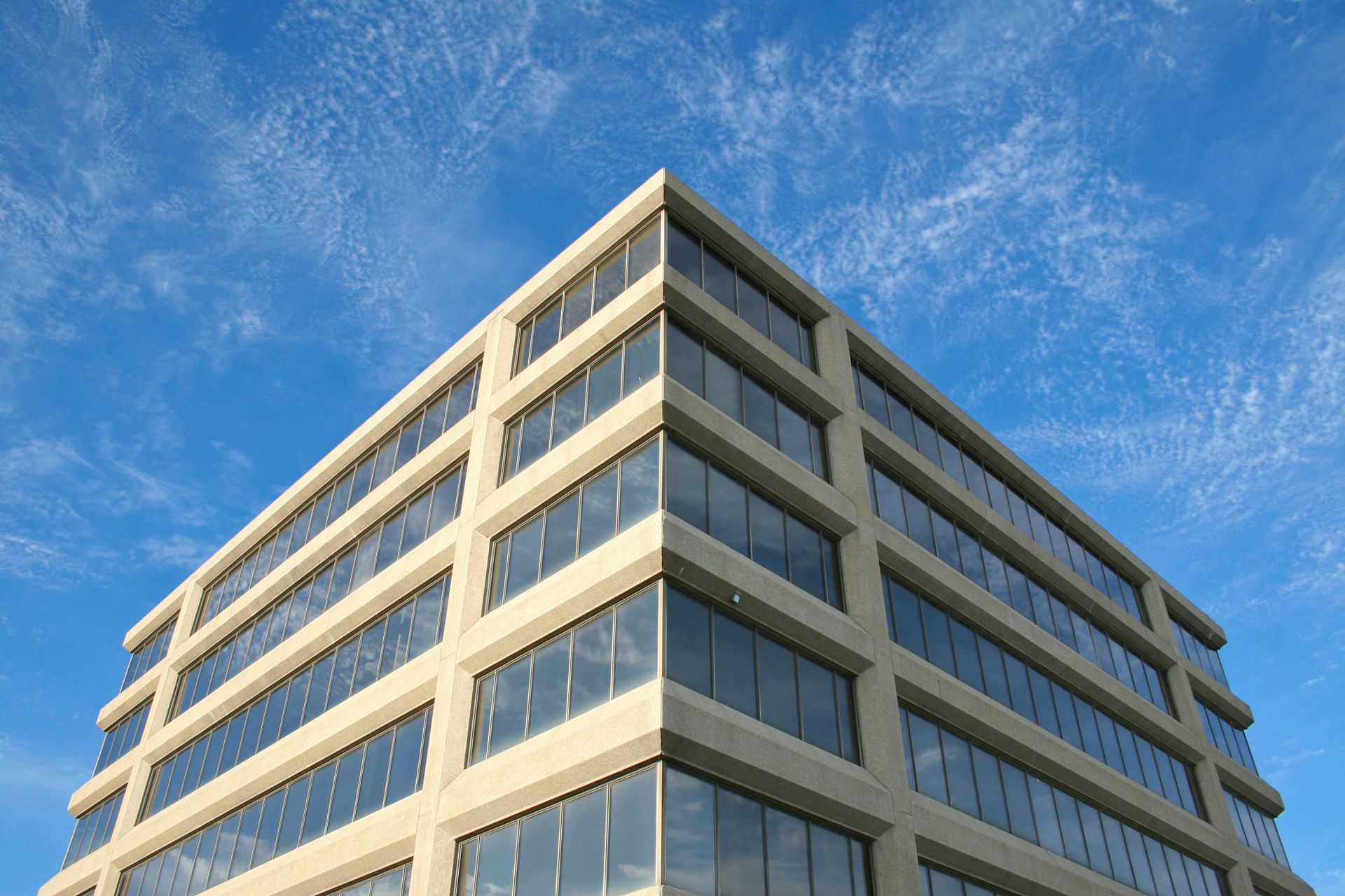 Modern office building with reflective windows against a blue sky