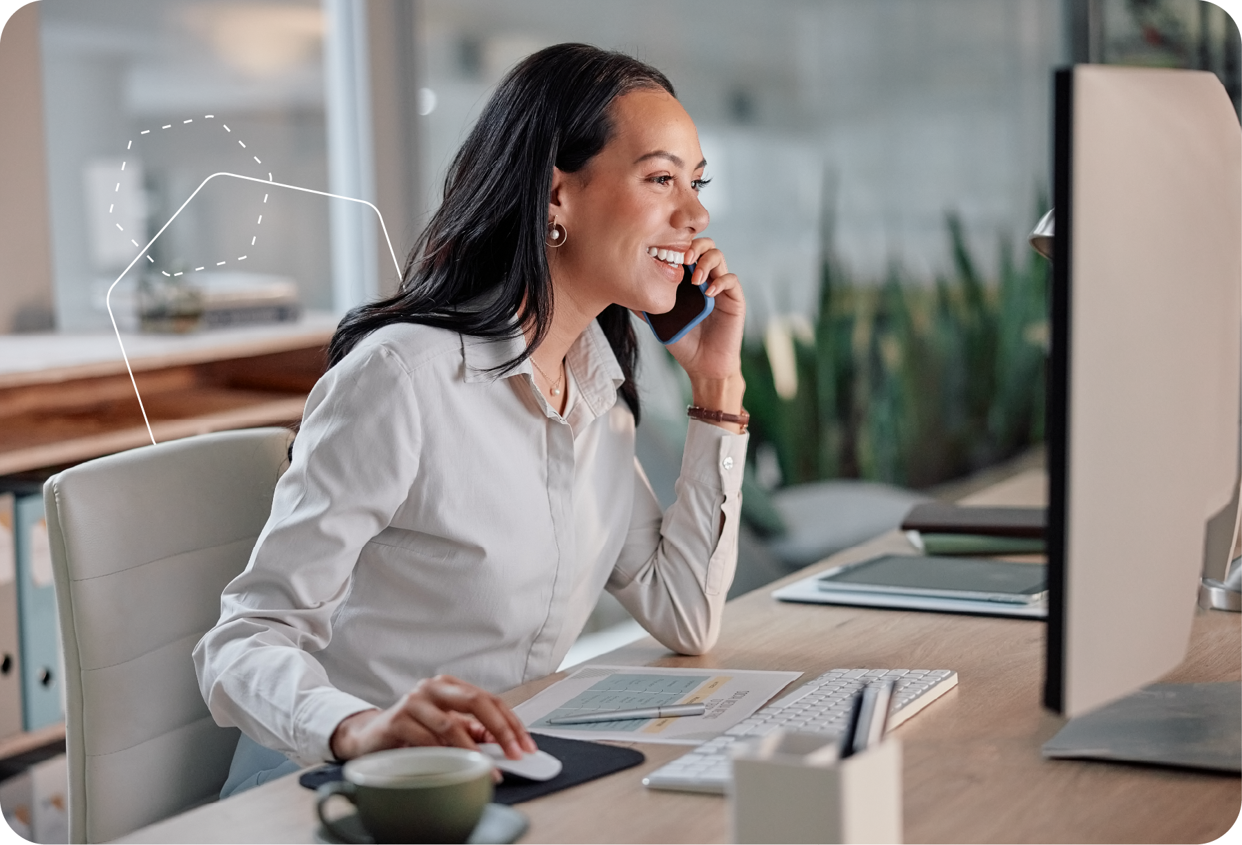 Person working at a desk and smiling while looking at a computer monitor in an office