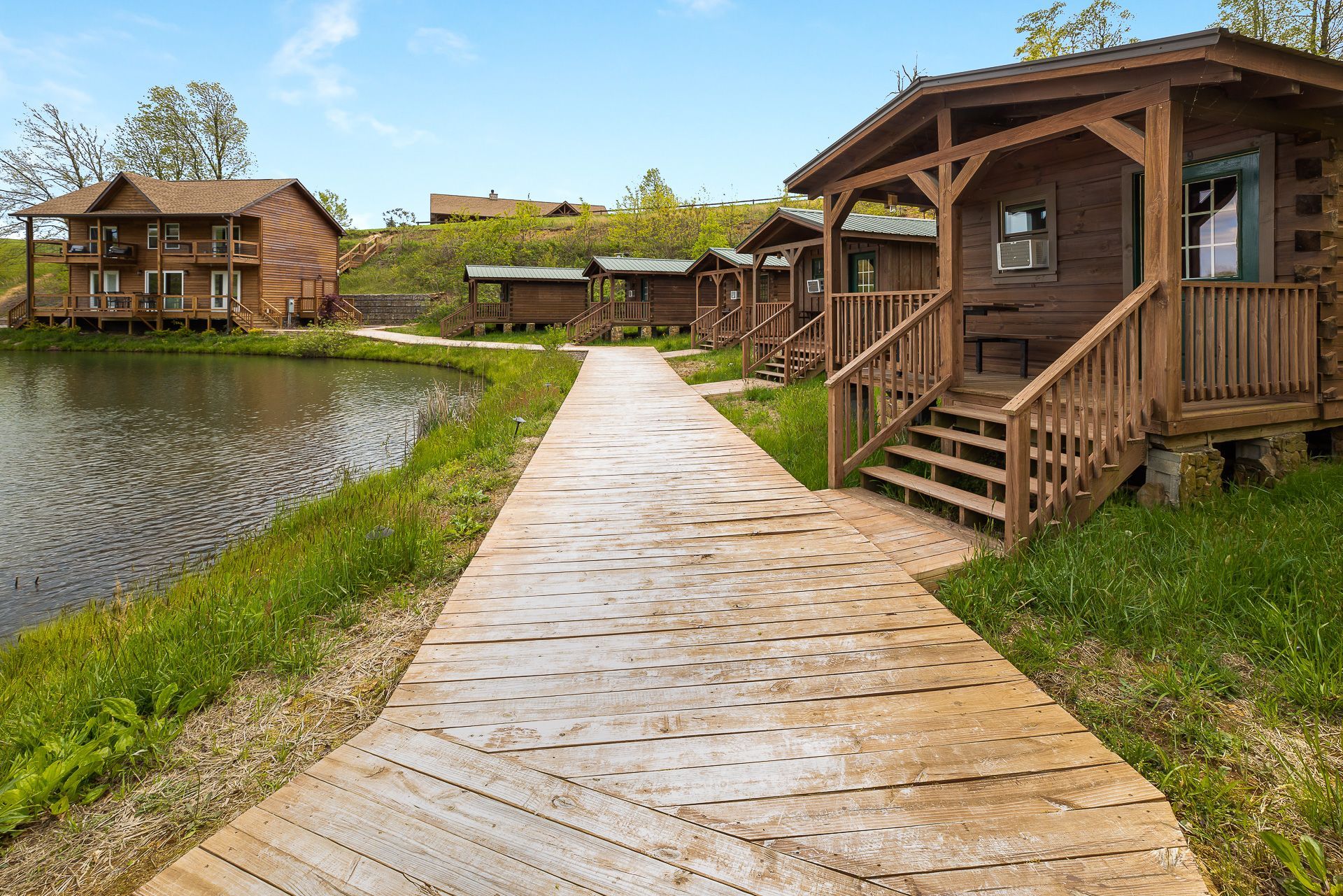 A wooden path leading to a row of cabins next to a lake.