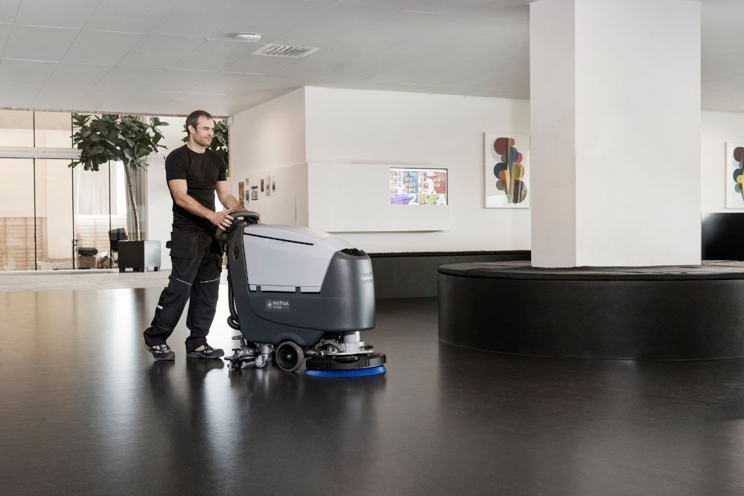 A man is cleaning the floor of a building with a machine.