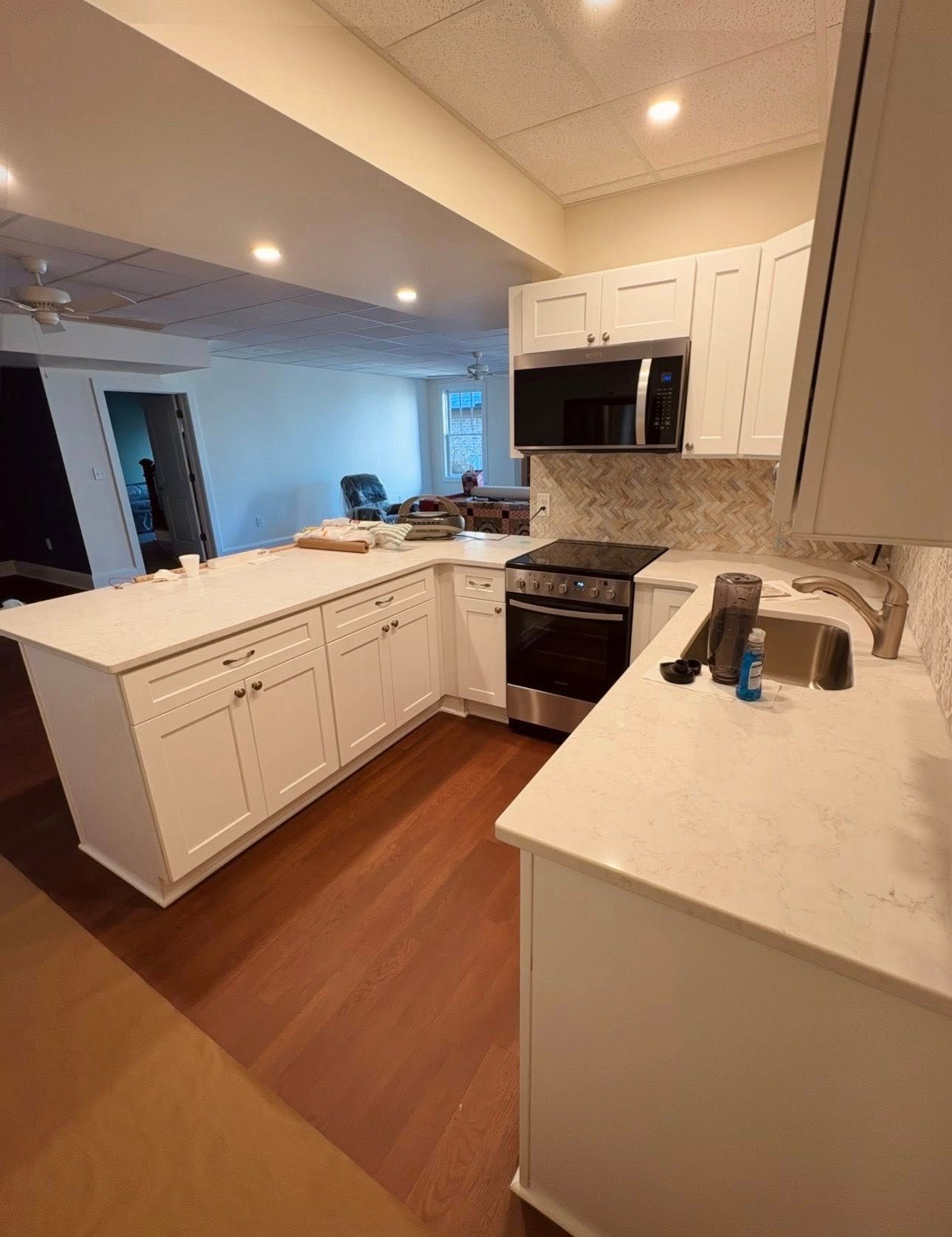 Bright modern kitchen with white cabinets, marble countertops, and stainless steel appliances.