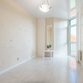 Bright empty white room with high windows, a small plant on a table, and a hanging light fixture
