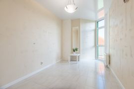Bright empty white room with high windows, a small plant on a table, and a hanging light fixture