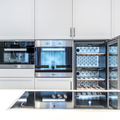 Modern built-in kitchen with white cabinets and stainless steel appliances, including an open wine fridge