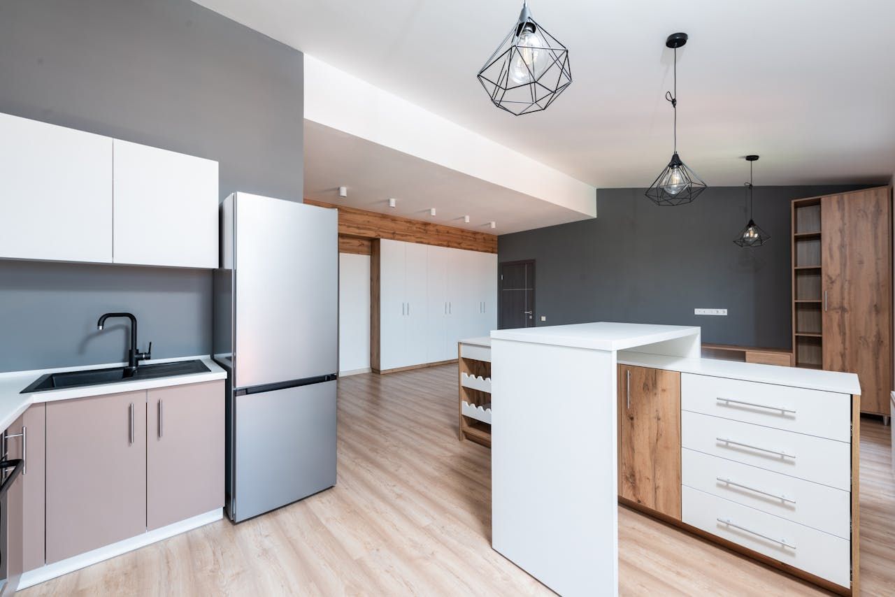 Modern open-plan kitchen with white cabinets, wood accents, island, and light wood floors