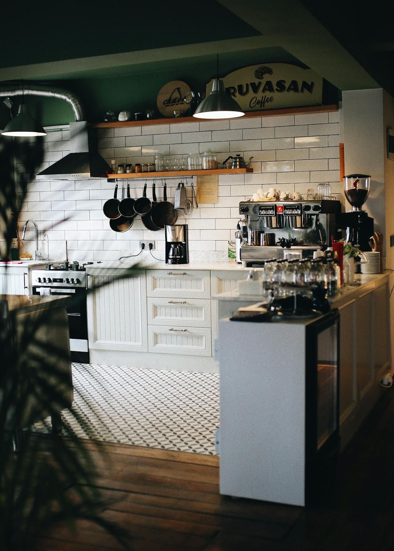 Cozy kitchen with white cabinets, hanging pans, and a coffee machine on the counter
