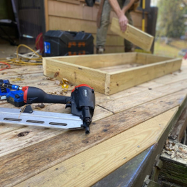 Small modern bathroom with white marble tiles, vanity sink, toilet, and bathtub/shower combo Construction tools on a wooden workbench beside a partially built wooden frame outdoors