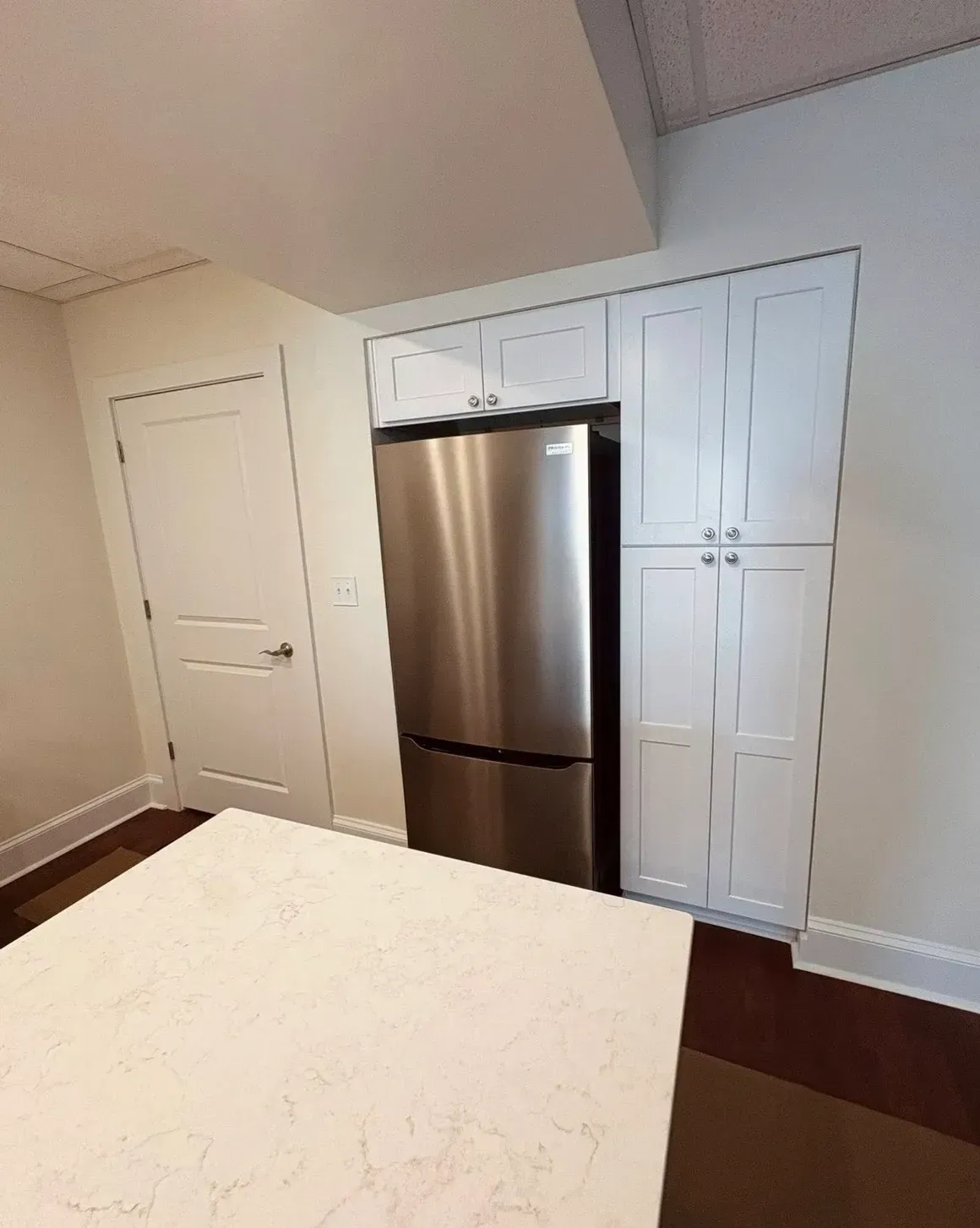 Bedroom with stainless steel refrigerator, white closet doors, and a bed in the foreground
