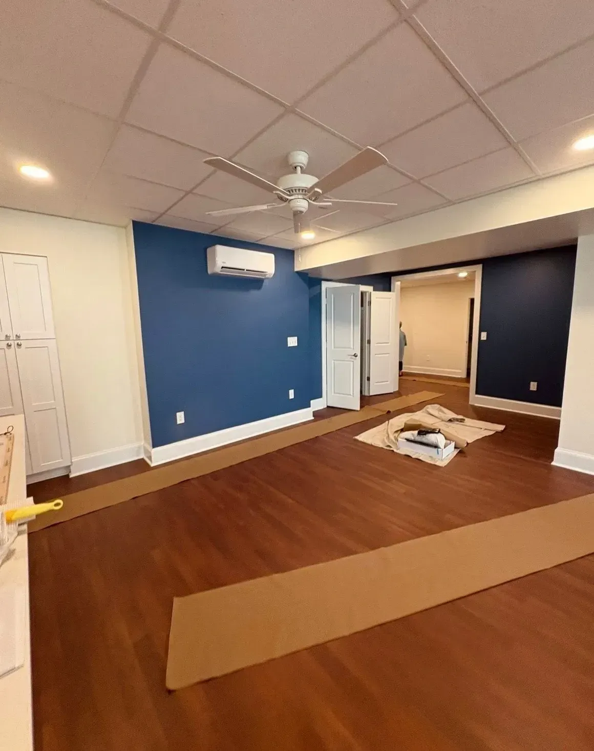 Empty room with blue walls, wood floor, ceiling fan, and a cardboard box on the floor.