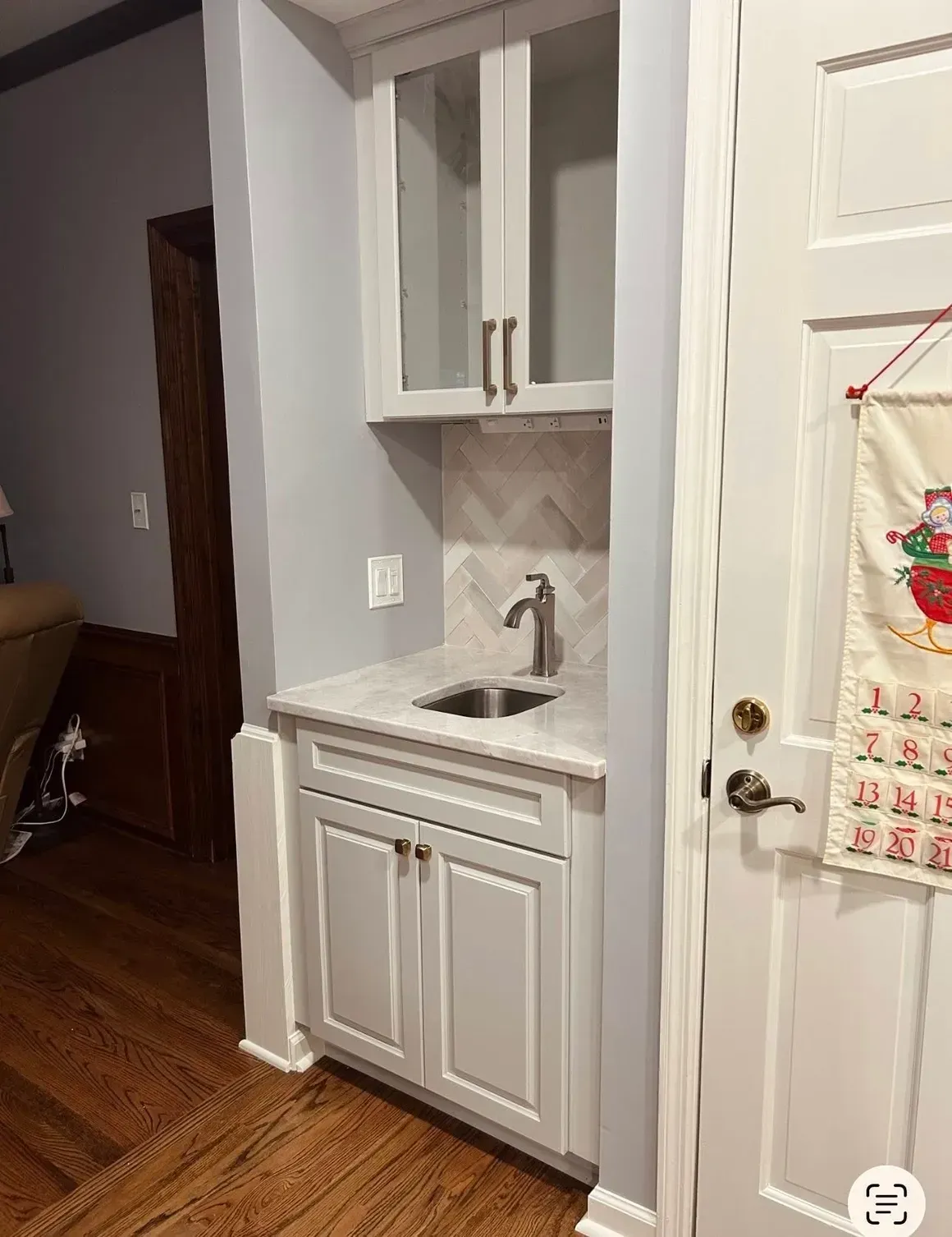 Built-in white vanity with sink and cabinet in a hallway, beside a door and hardwood floor