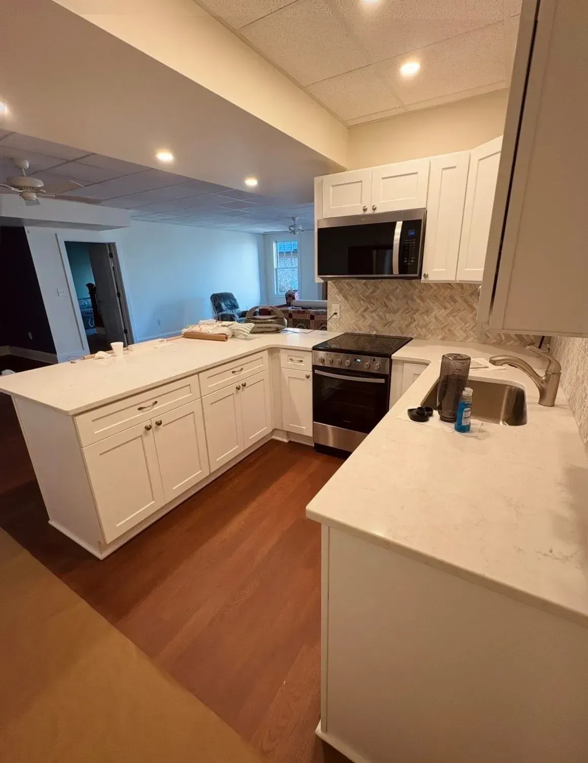 Bright modern kitchen with white cabinets, stainless appliances, and wood floors in an open living space