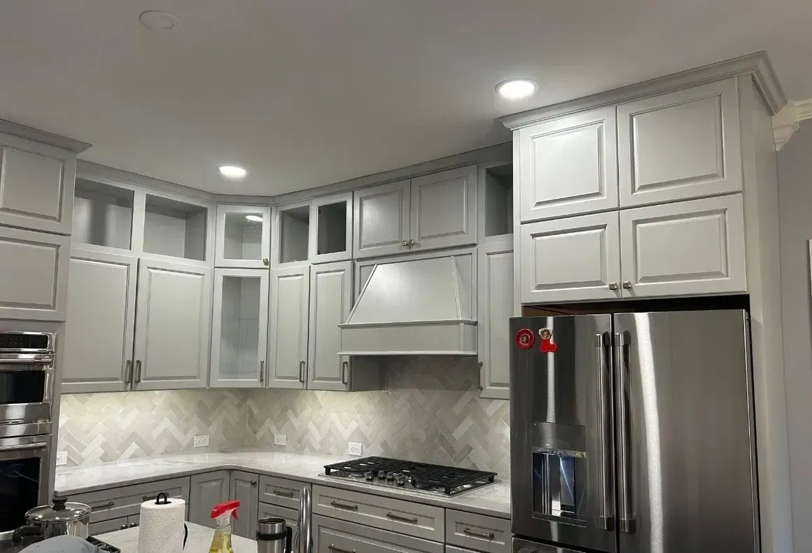 Modern white kitchen with gray tile backsplash, stainless fridge, stove, and built-in cabinets