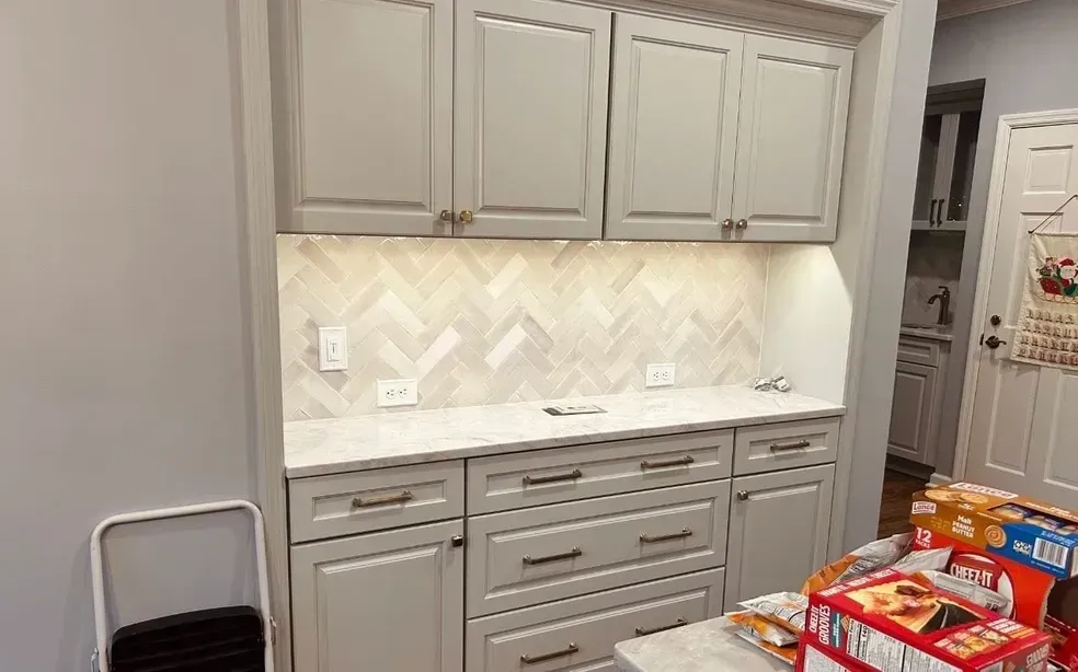 Built-in gray cabinets and countertop with herringbone backsplash in a kitchen nook