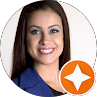 Smiling woman with dark hair in a blue jacket, shown in a circular headshot with an orange star badge.