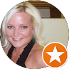 Smiling blonde woman in a black top, with an orange star badge in the corner