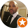 Profile photo of a person in a black suit and tie, holding a phone, with an orange star badge overlay.
