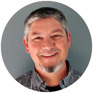 A man with gray hair and a beard is smiling in a circle.