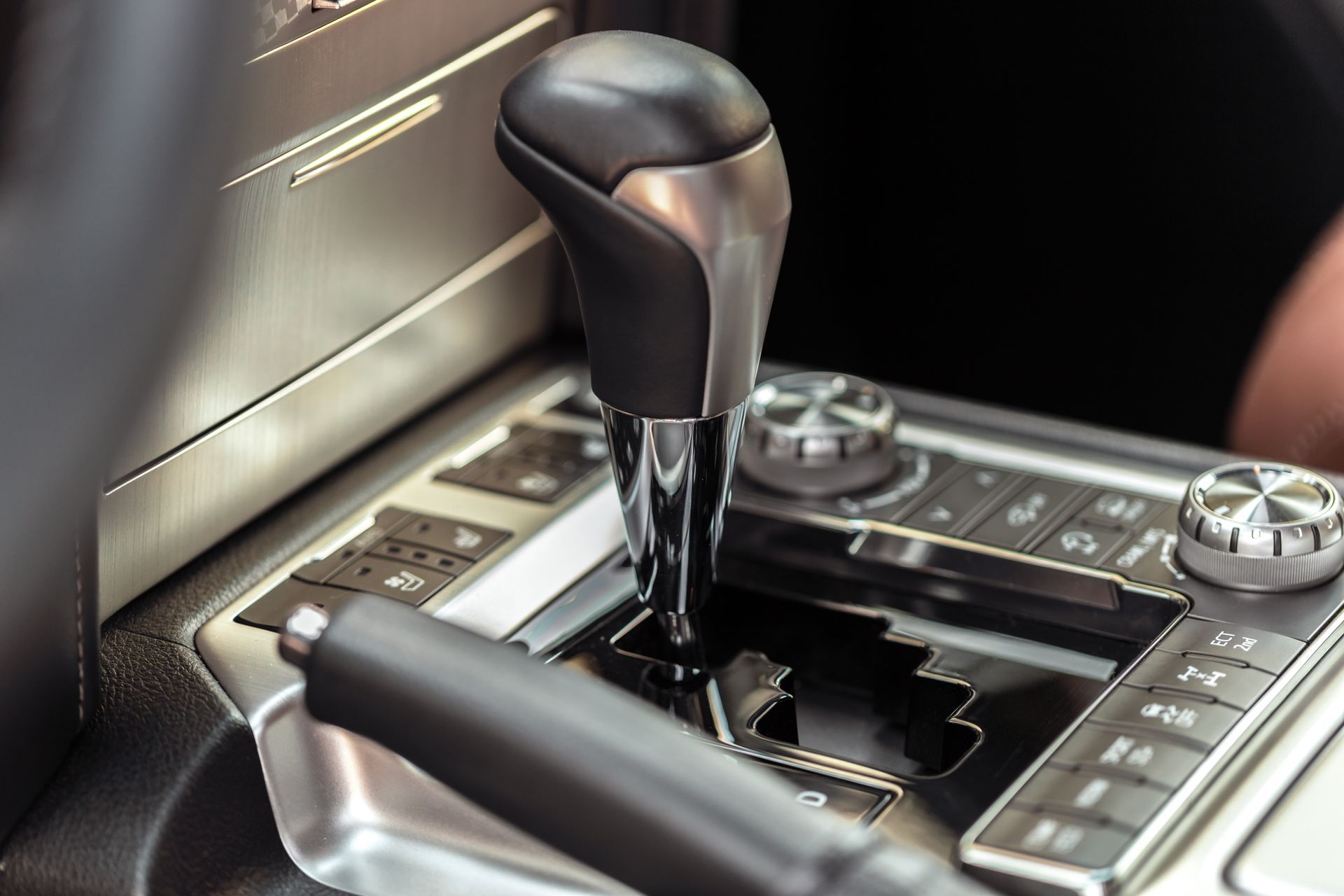 Car gear shift and center console with metallic controls and black leather trim