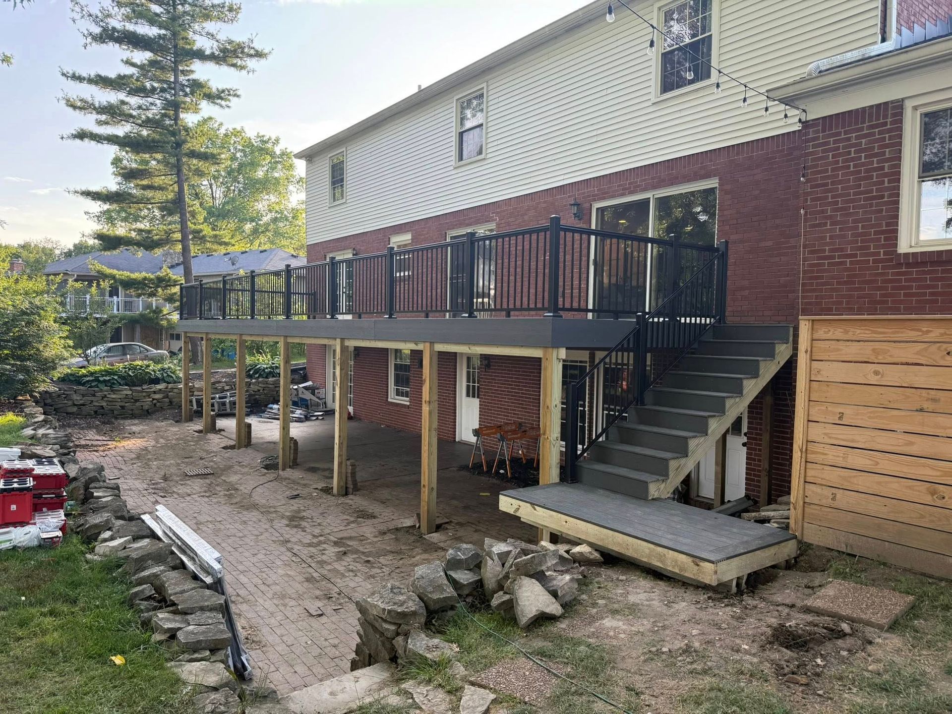 Newly built deck with black railing and stairs attached to a brick house.