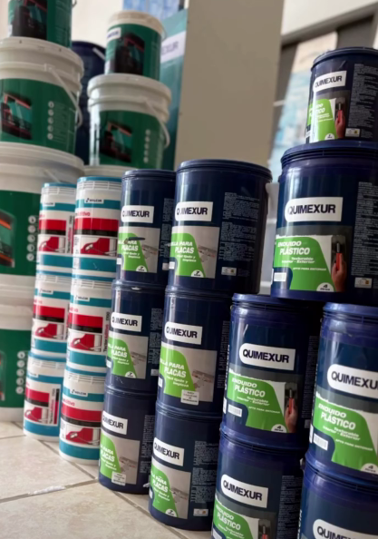 Pilas de cubos de pintura blancos, verdes y azul marino en el pasillo de una tienda.