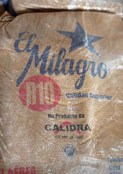 Bolsa de café marrón con la etiqueta “El Milagro Rio”, un logotipo de estrella y la palabra “Calidad” en español.