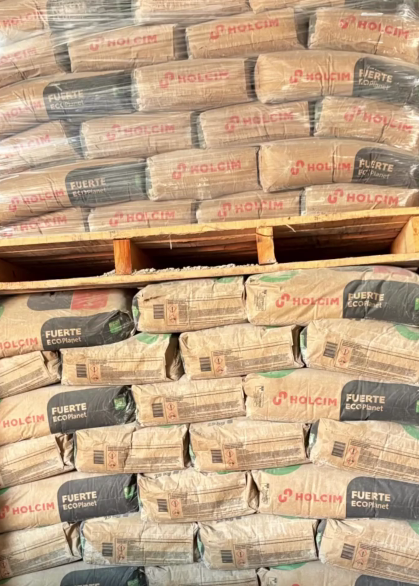 Sacos de cemento apilados sobre un palé de madera en un área de almacenamiento.