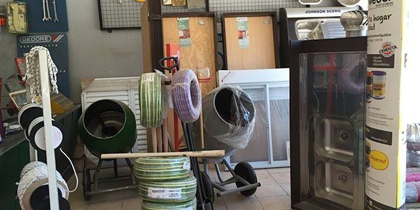 Exhibición de la tienda con alfombras enrolladas, muestras de pisos y una vitrina para electrodomésticos.