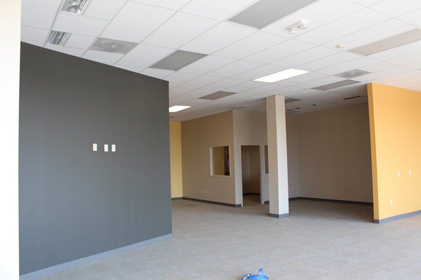 Empty commercial office space with gray and yellow walls, carpeted floor | 