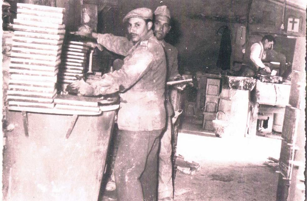 Tre uomini lavorano in un laboratorio. Due sono in piedi in primo piano, un altro lavora dietro.