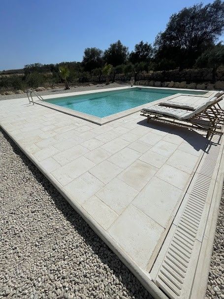 Rivestimento rettangolare in pietra beige chiaro installato con un motivo a correre su una base a muro, con stucco liscio .