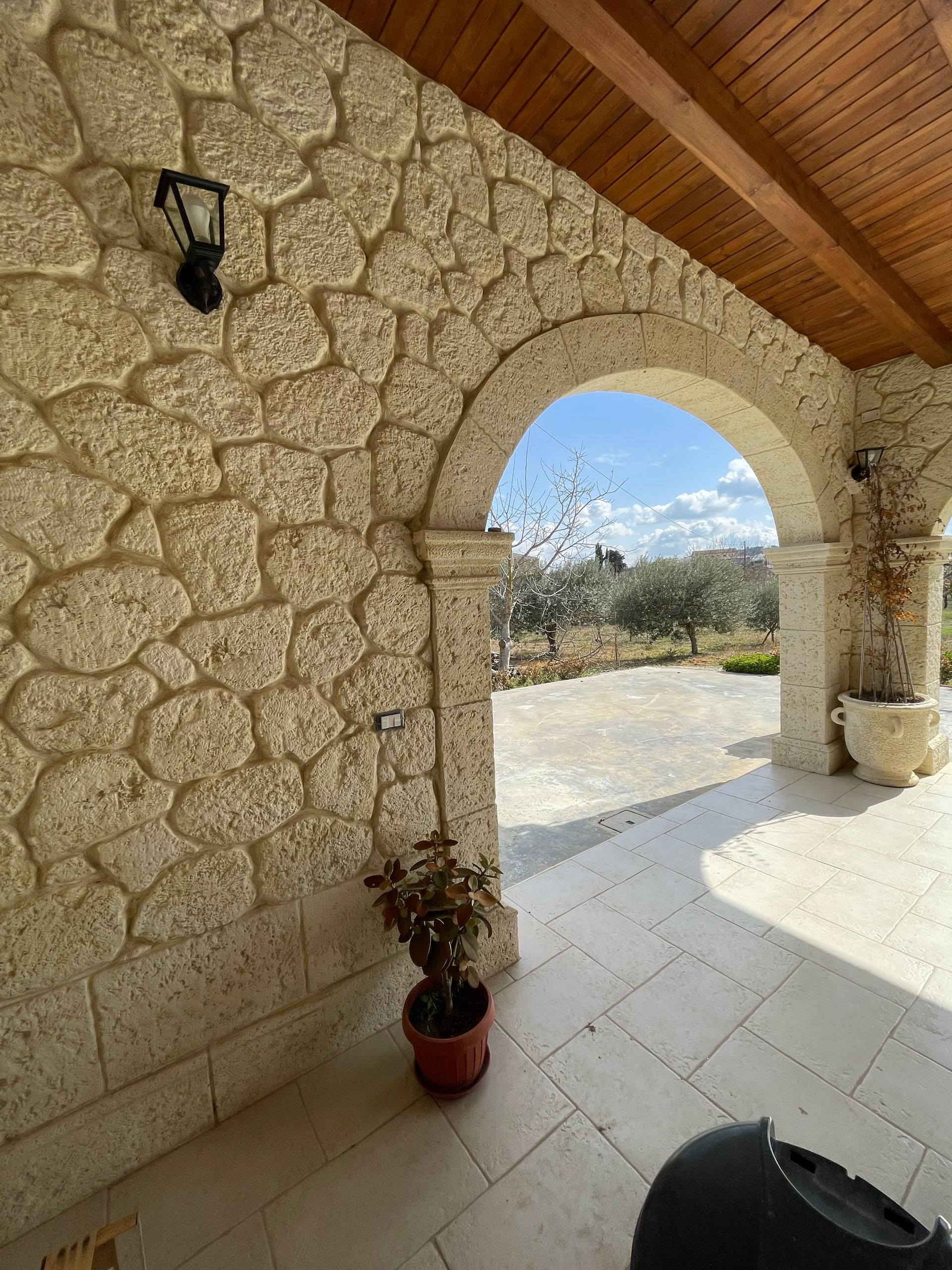 Una casa gialla con un portico anteriore ad arco bianco e una balaustra in pietra coordinata sul balcone superiore.