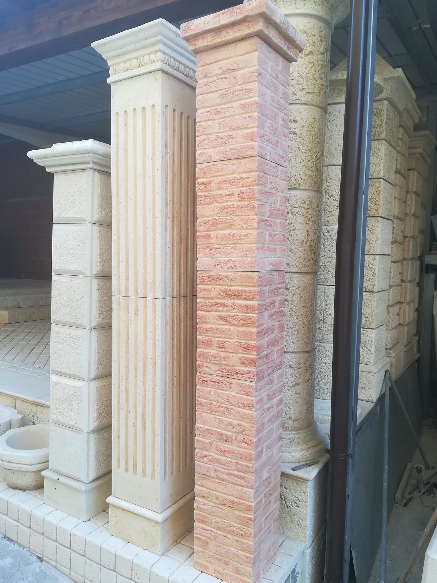 Numerose colonne e pilastri decorativi in pietra, disposti verticalmente, presentano diverse texture e tonalità beige.