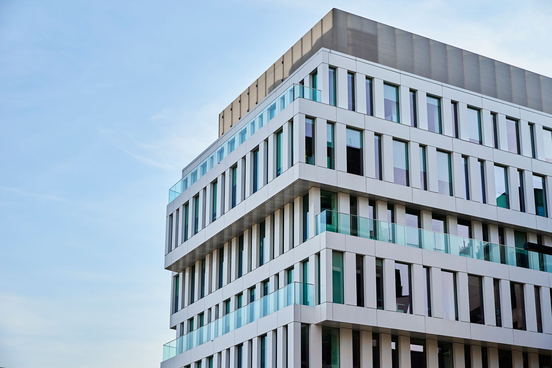 Modern white office building with vertical windows against a blue sky